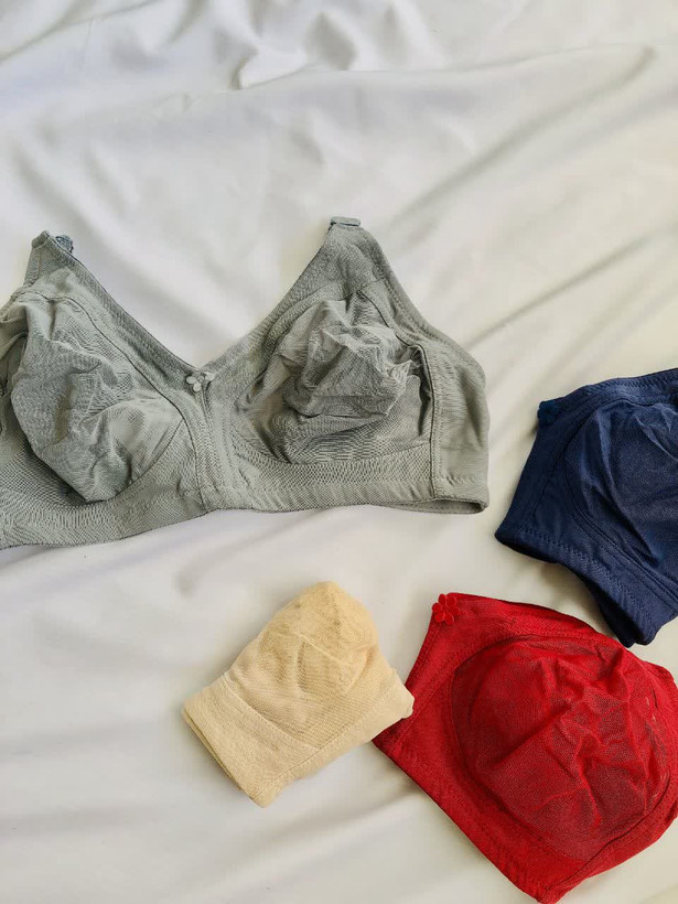 چهار سوتین زنانه پرسی بدون فنر در رنگهای طوسی، سرمهای، قرمز و کرم روی سطح سفید چیده شدهاند؛ طراحی ساده، بدون دوخت و مناسب استفاده روزانه